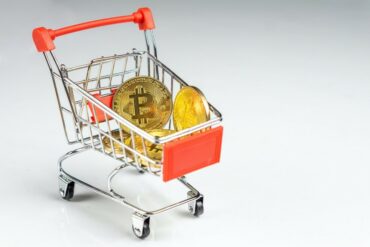 Miniature shopping cart with gold bitcoins.