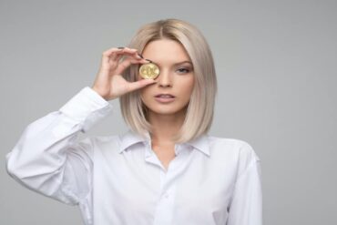 Woman holding a Bitcoin to her eye
