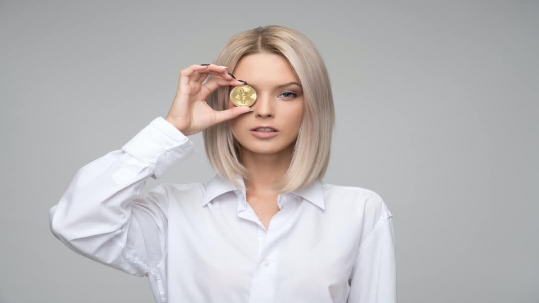 Woman holding a Bitcoin to her eye
