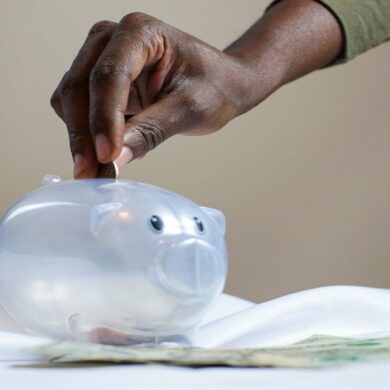 Person putting a coin in a piggy bank